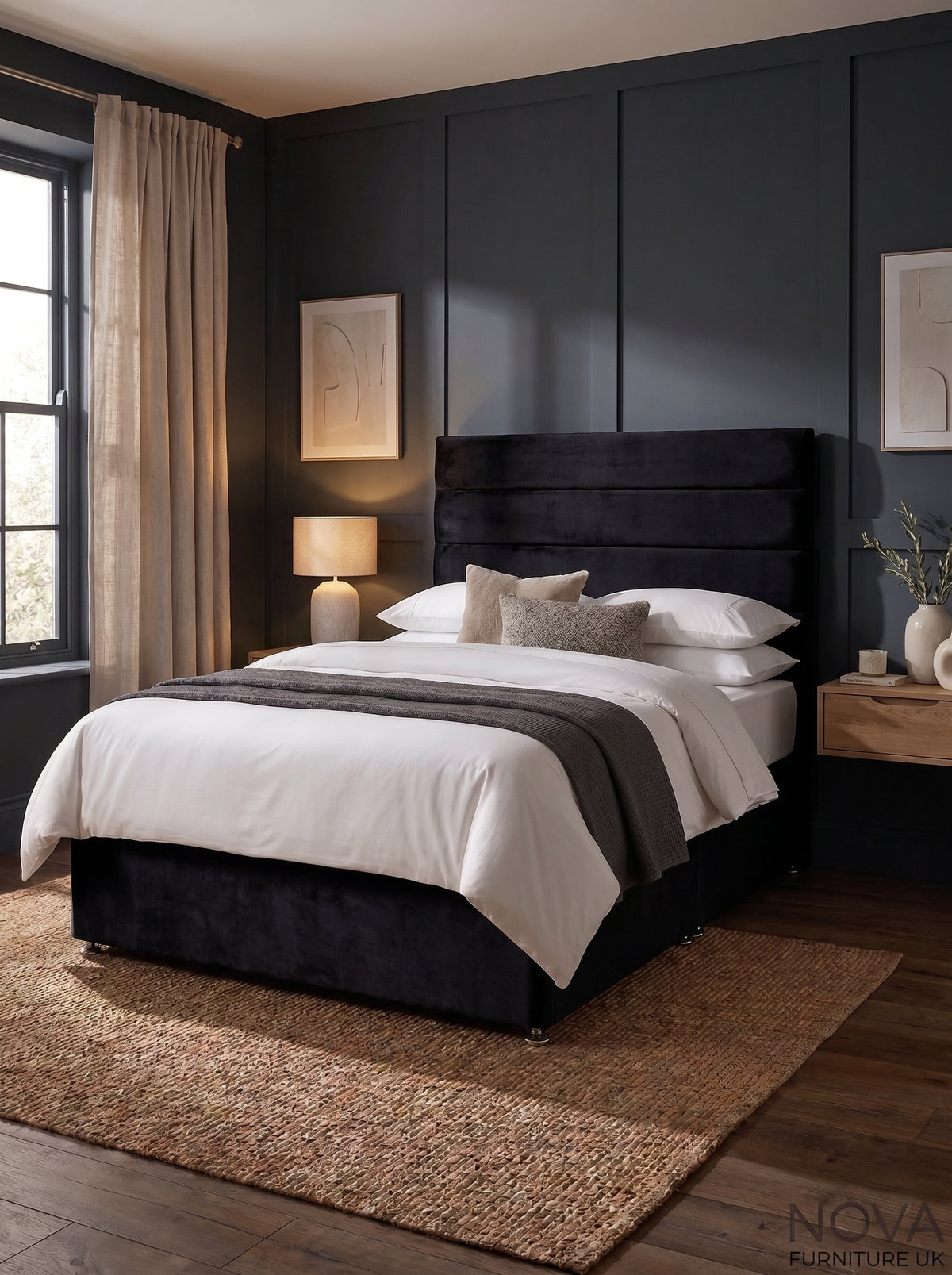 A dark upholstered bed frame with a tall padded headboard, dressed in white bedding and a gray throw, set in a modern bedroom with dark paneled walls, a window, curtains, and a woven rug.