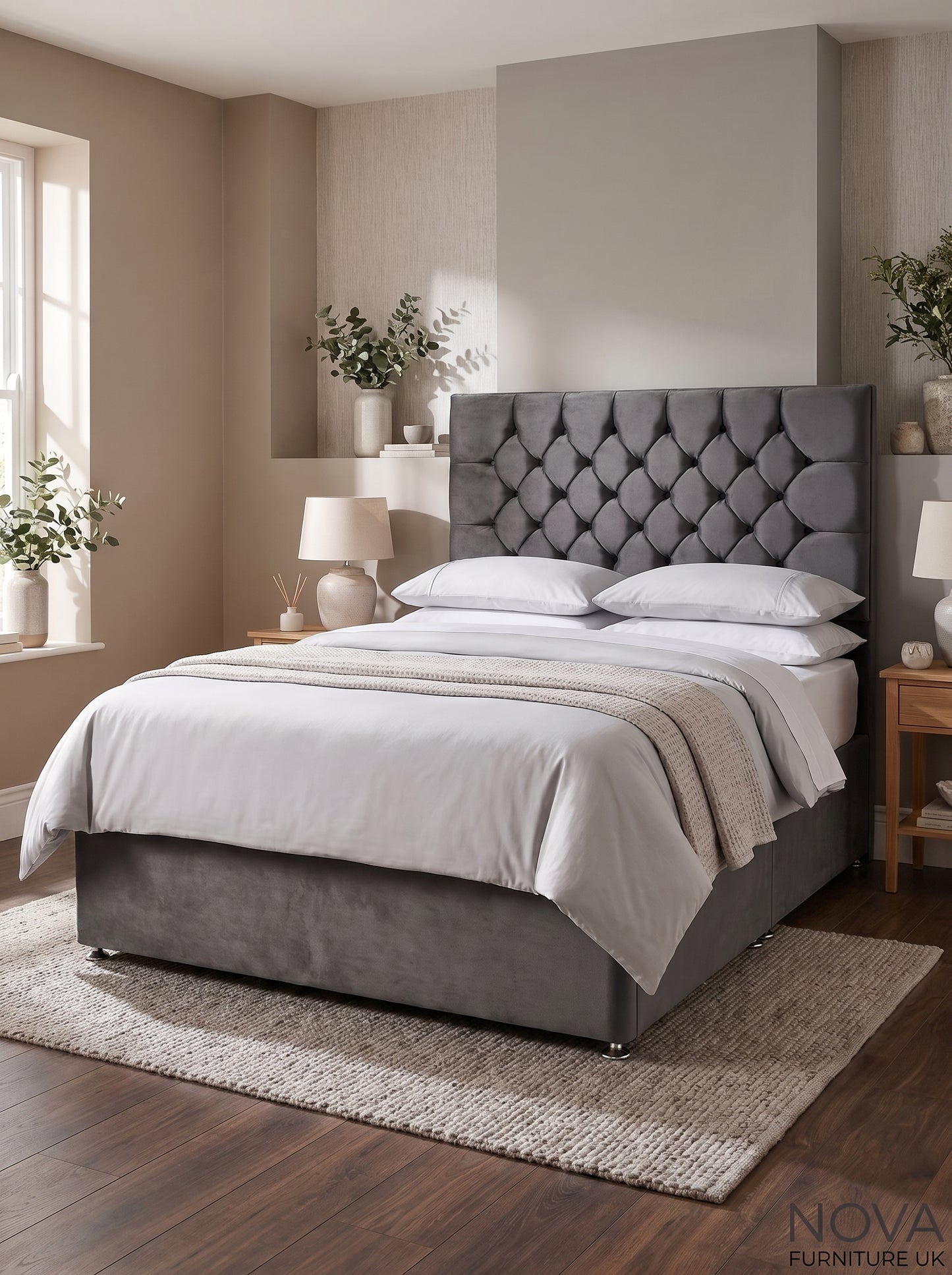 A gray upholstered bed with a tufted headboard and matching footboard, shown in a styled bedroom with white bedding, bedside tables, lamps, plants, and wood flooring. A 'NOVA FURNITURE UK' logo is visible in the bottom right corner.